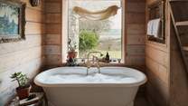 Beside a pretty picture window is a French cast iron bathtub - the prettiest bubble-topped scenes await