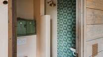 Adjacent is a shared shower room, with olive green Lume Musk tiles and stylish micro-cement walls