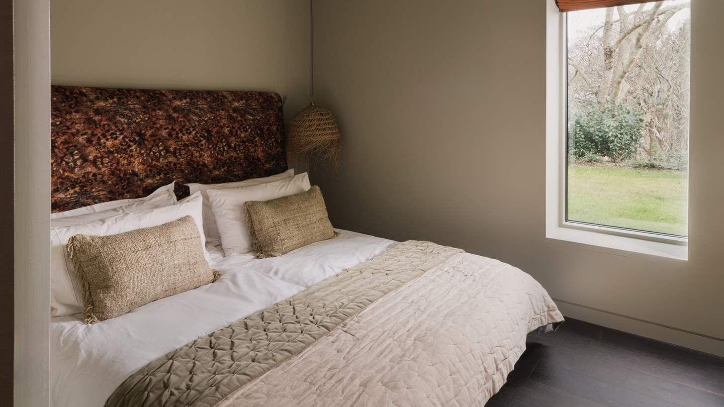 The stylishly simplistic bedroom features a king-size bed hugged by rustic pendant lighting