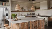 Set beneath dark wooden beams is the divine kitchen space, where reclaimed oak cabinetry and brass accents nod to the retreat’s rustic-influences