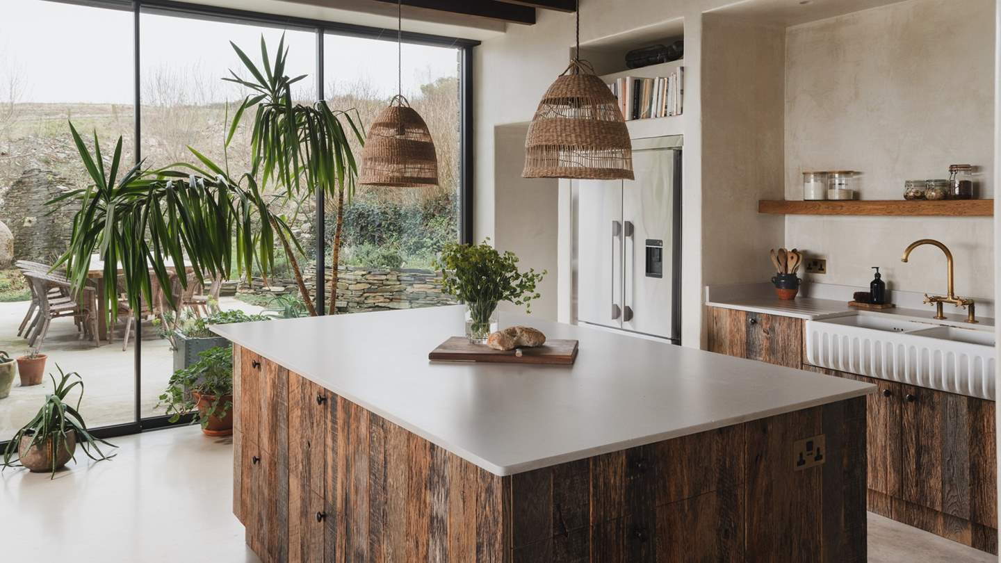 Taking centre stage beneath rattan pendant feature lighting is the spacious kitchen island