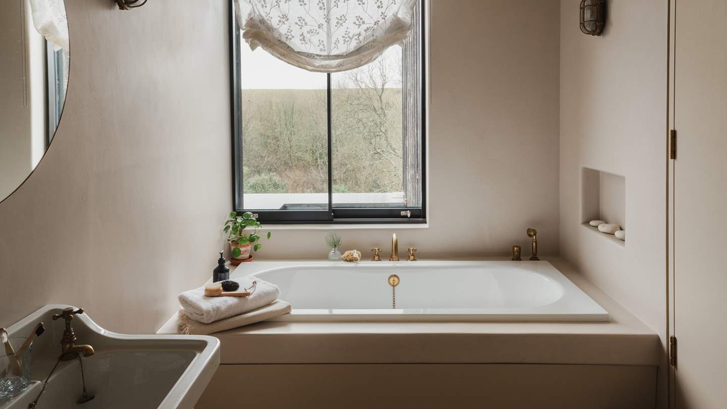 Tucked at the end of the hall is the sleek family bathroom with a traditional sink, where a built-in bathtub is framed by sheer floral voiles