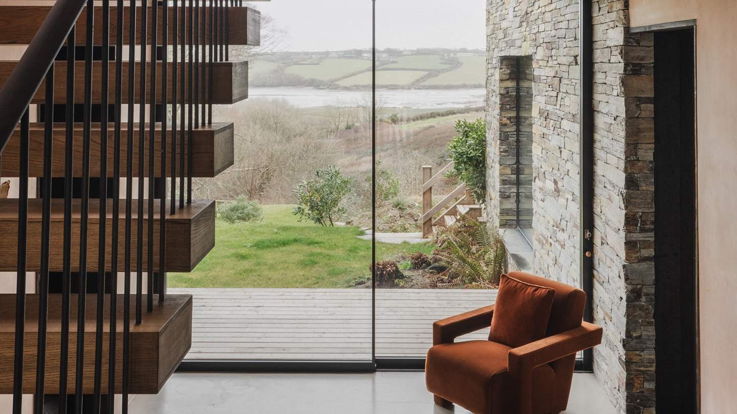 Greeted by dramatic views of an estuarine landscape and a mid-century-inspired hanging staircase crafted with chestnut timber, the entrance hall provides a warm welcome