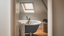 This bathroom benefits from a freestanding rolltop bath in shades of white and blue, idyllic for soothing soaks under the skylight