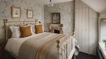 For those seeking extra space, the second bedroom in soft cream hues with mustard yellow inflections features an antique brass double bed