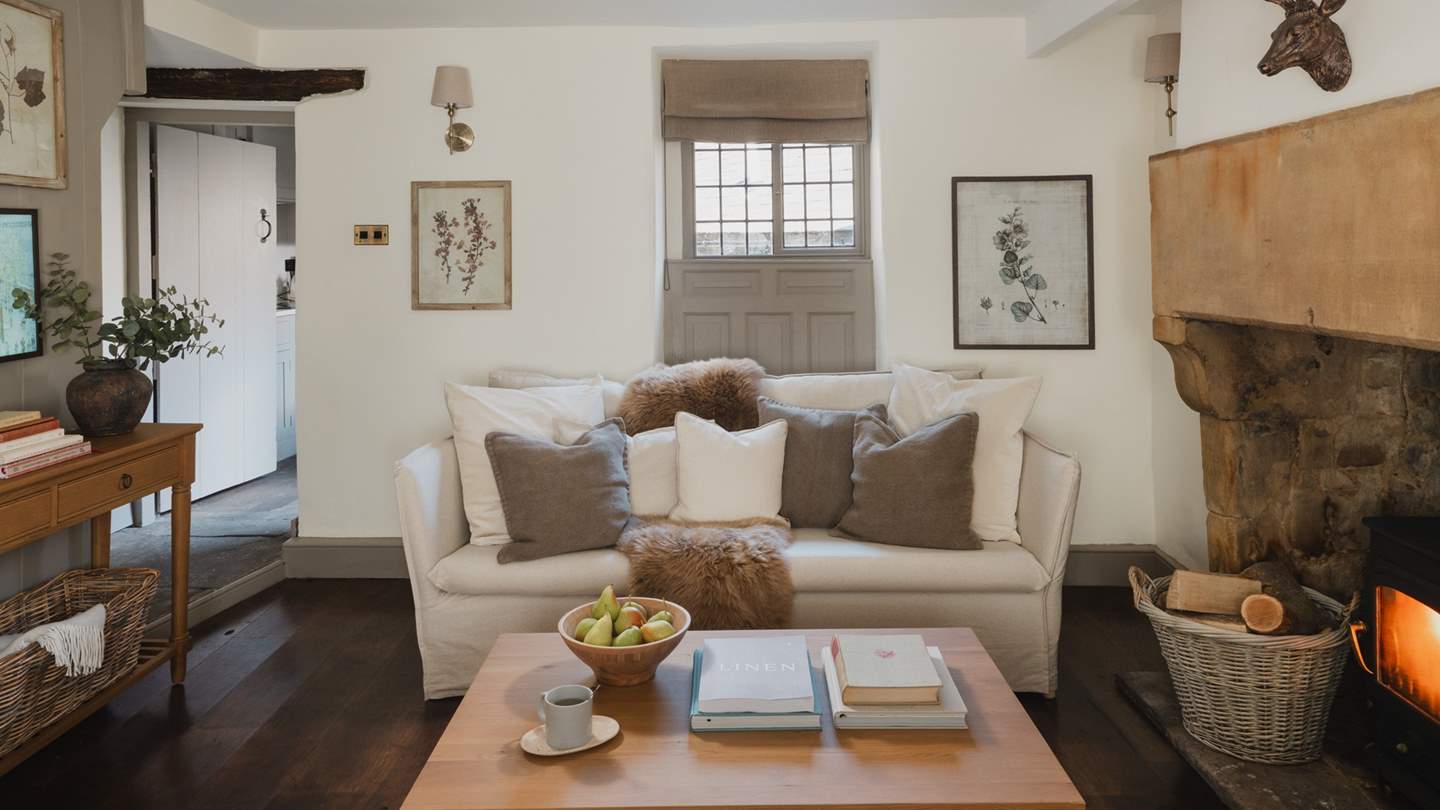 Two comfortable linen sofas lie either side of the wood burner to welcome cosy moments in the cooler months