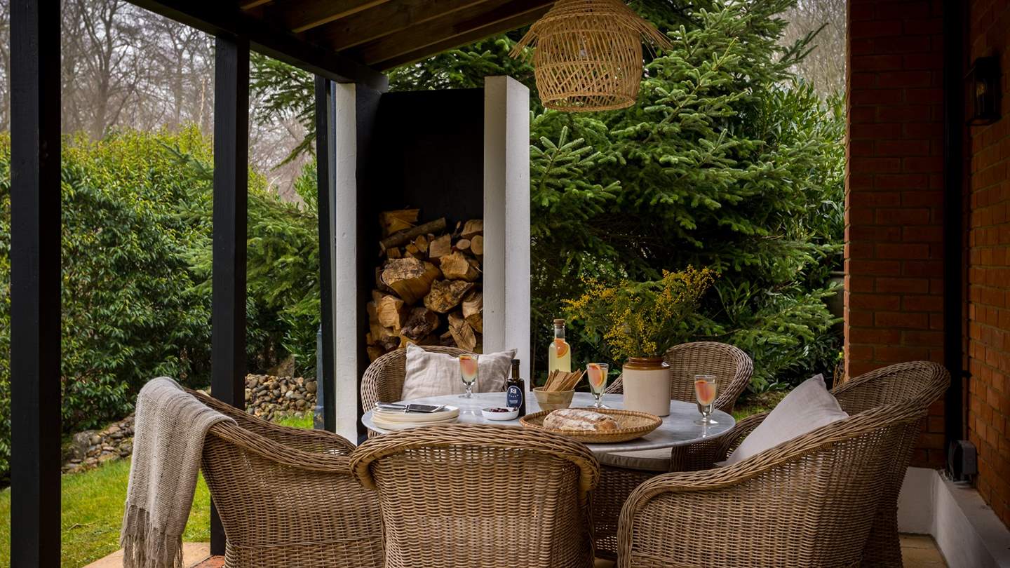 A round marble table and seating for six sits beneath an outdoor chandelier