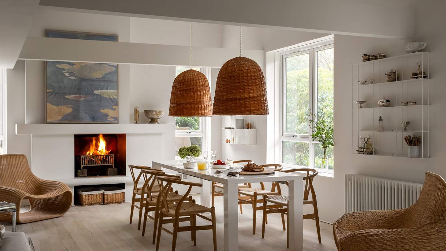 A large open fire is set within a modern minimalist fireplace, adding warmth to the space as you dine and relax