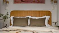 A rattan headboard, wooden bedside tables and a rustic woven chair add touches of calm to the room
