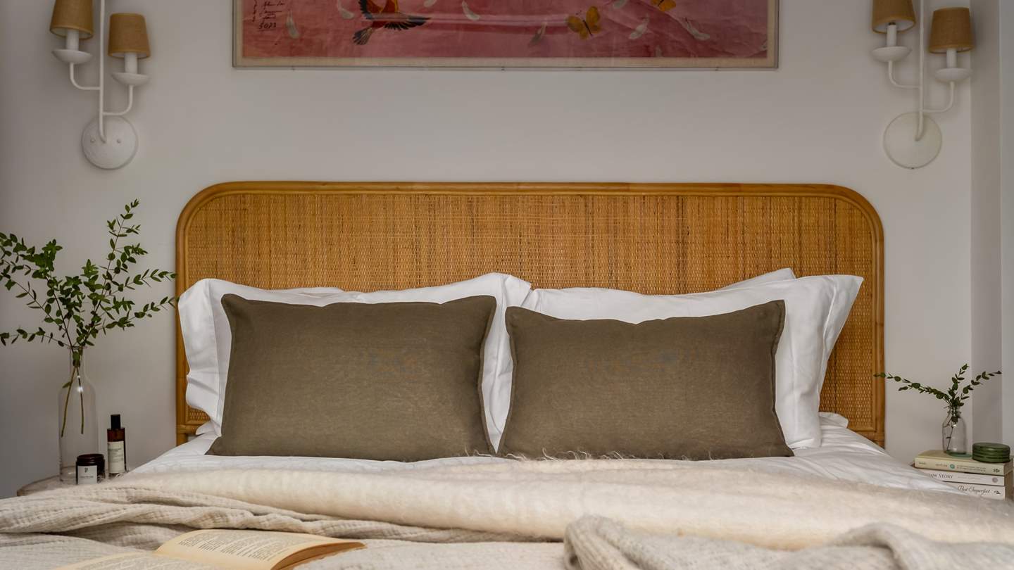 A rattan headboard, wooden bedside tables and a rustic woven chair add touches of calm to the room