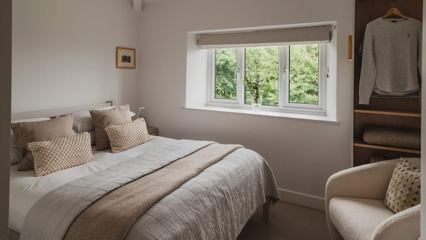 A boucle armchair rests beside the open shelving and wardrobe