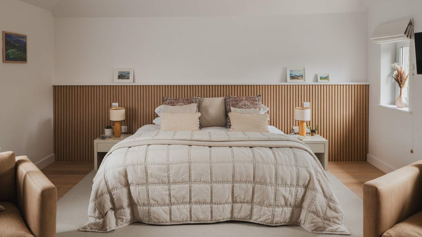 With a half panelled wooden feature wall, the spacious fifth bedroom is incredibly inviting