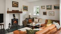 A second wood burning stove can be found before a large leather U-shaped sofa
