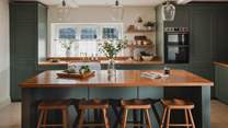 Resting centre in the kitchen beneath delicate glass pendants is the wooden-topped island, with four oak stools for casual brunches