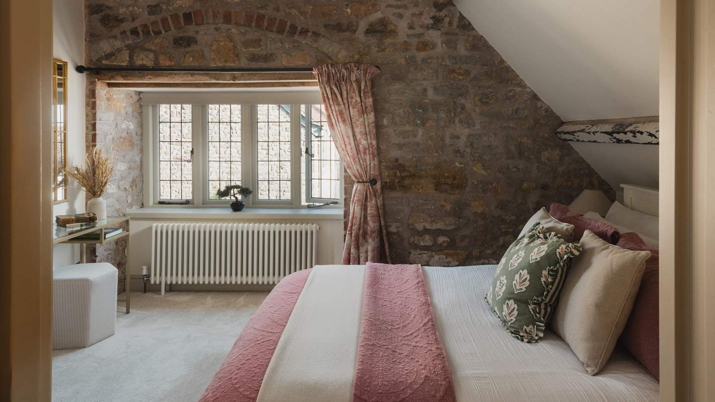 With a king size bed and a stone feature wall, this bedroom is adorned in darling pink hues 