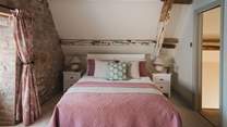 With beautifully distressed exposed beams, the second bedroom is a calming space for lingering lie-ins