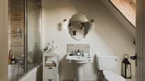The stunning, vaulted en suite bathroom offers a bath with an overhead shower
