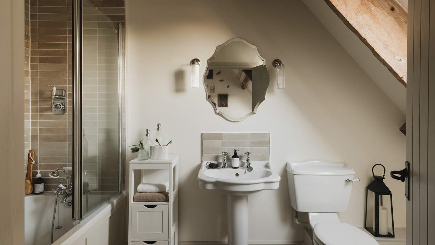 The stunning, vaulted en suite bathroom offers a bath with an overhead shower