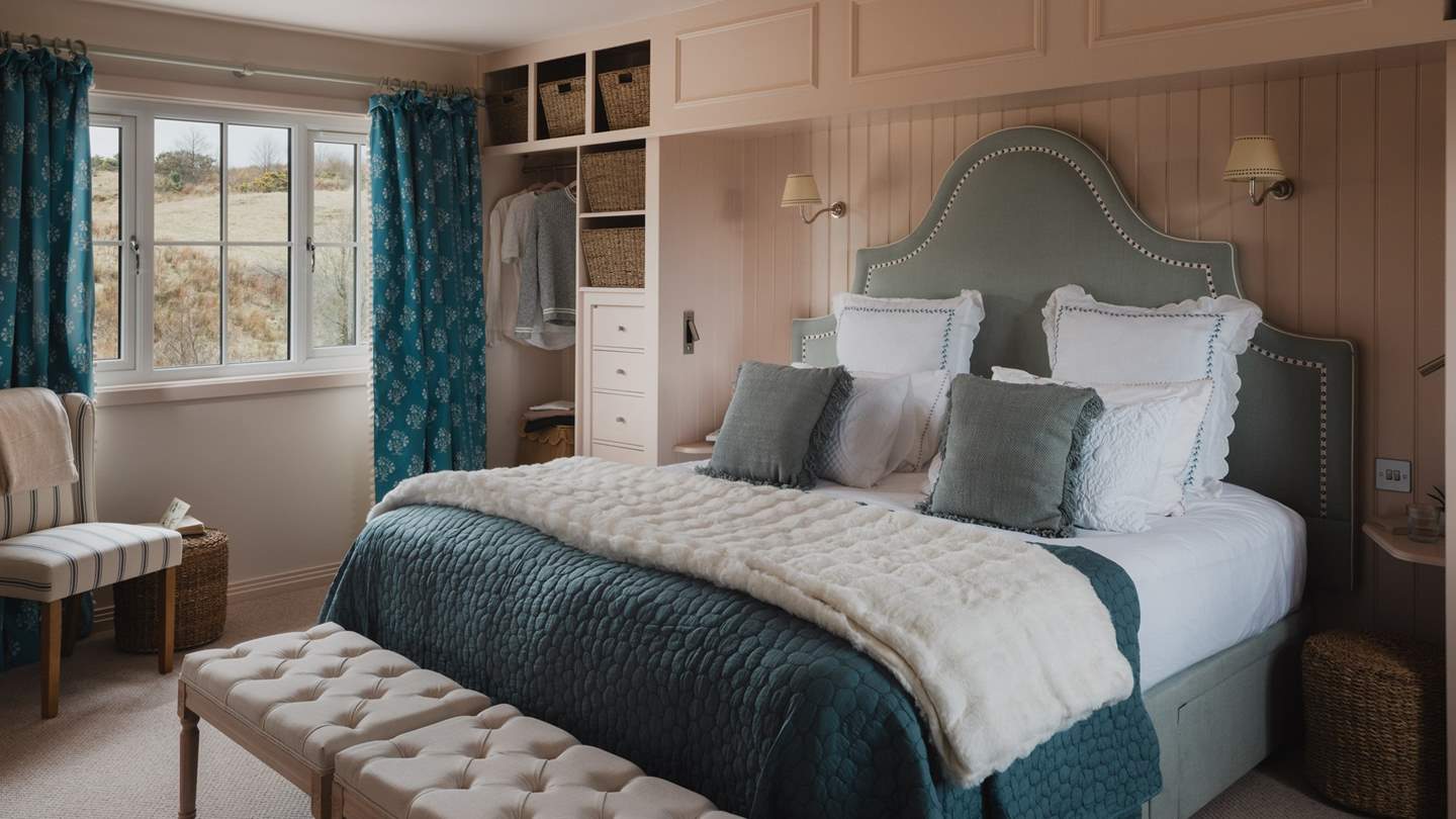 Bedroom two is equally inviting, with built-in storage and hanging space either side of the bed creating a nook for the striking blue headboard