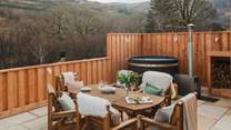 A table and chairs for six rests to the side of the retreat, with the addition of a wood-fired hot tub