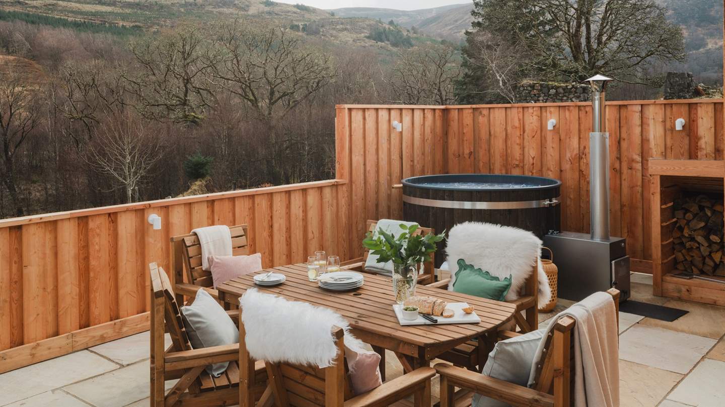 A table and chairs for six rests to the side of the retreat, with the addition of a wood-fired hot tub