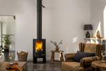 Gather beside the stylish wood burning stove on a choice of seating, from the tan leather sofa to the cosy Nkuku Kilim armchairs