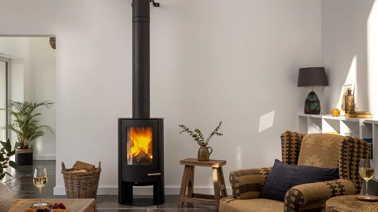 Gather beside the stylish wood burning stove on a choice of seating, from the tan leather sofa to the cosy Nkuku Kilim armchairs