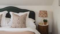 The green velvet scalloped headboard beautifully complements the cushions, throws and floral artwork