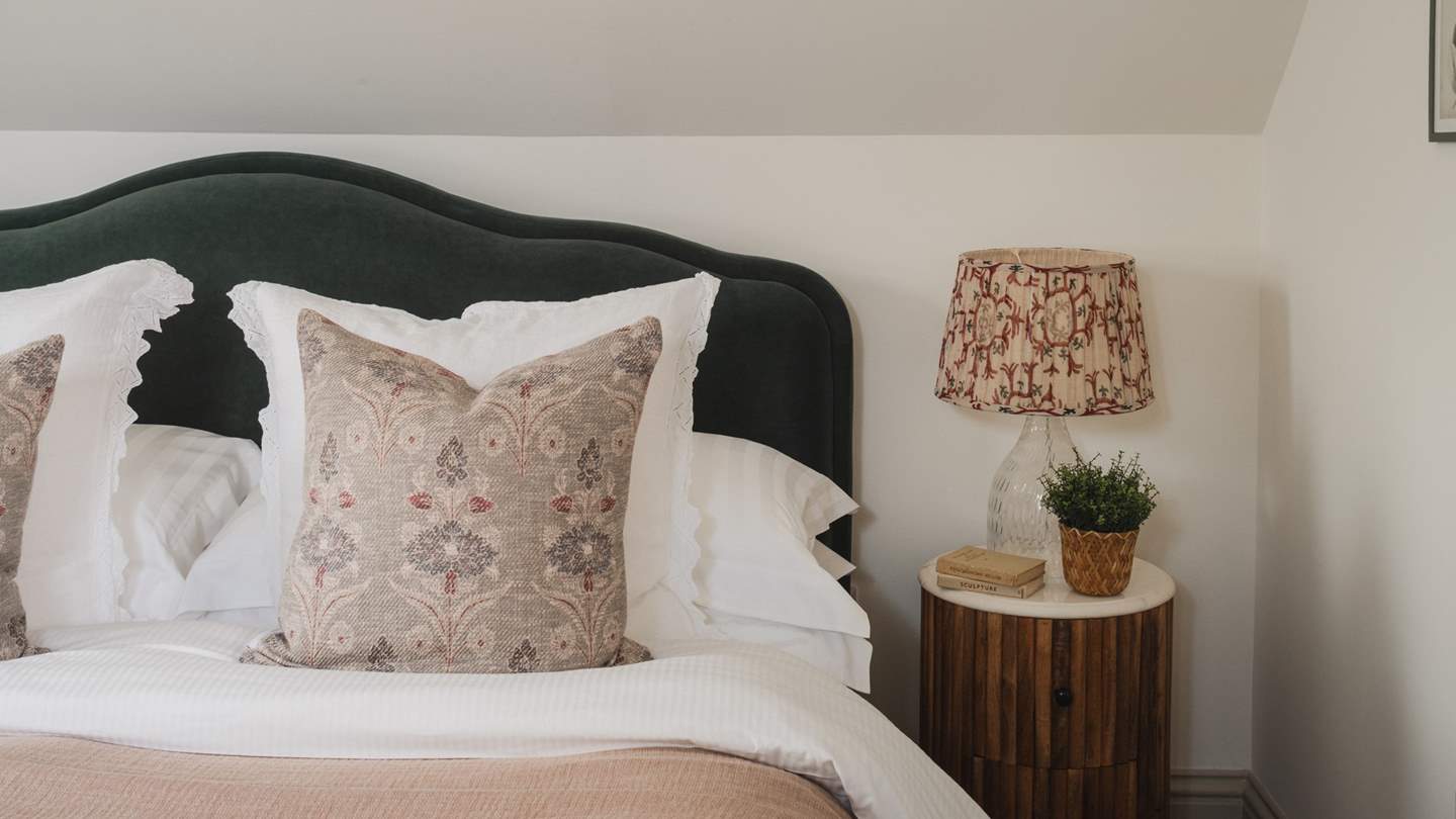 The green velvet scalloped headboard beautifully complements the cushions, throws and floral artwork