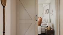 Nestled behind a sliding barn door, the master bedroom is designed in soothing shades