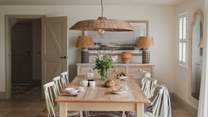 A farmhouse style dining table for six is positioned before large patio doors