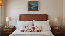 An upholstered terracotta headboard creates a luxurious space to unwind