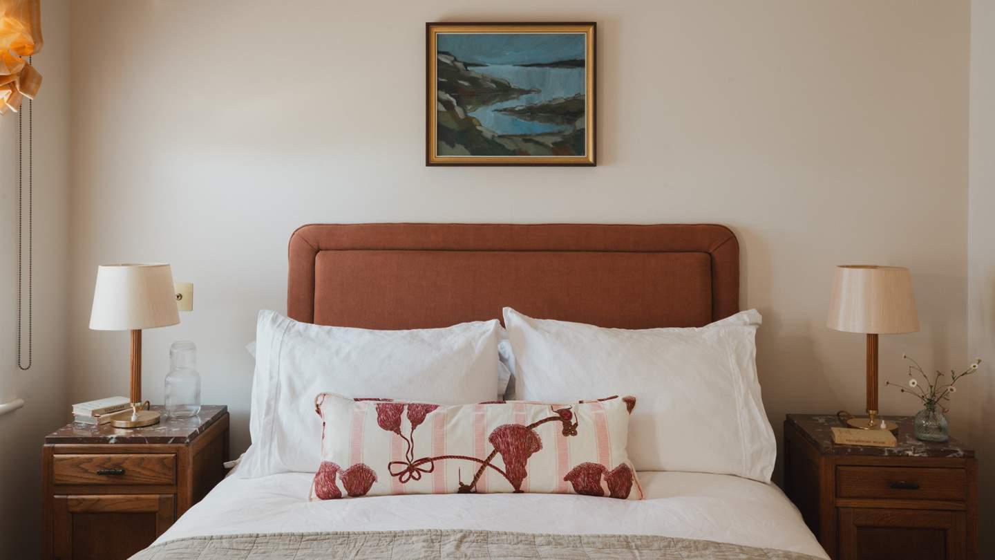 An upholstered terracotta headboard creates a luxurious space to unwind