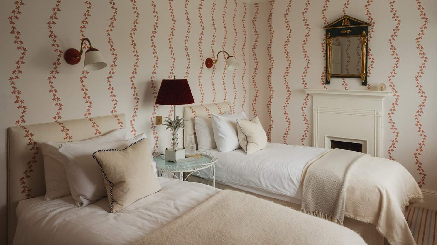 Beautifully clever symmetry of the wallpaper and headboards ensures a cohesive design scheme