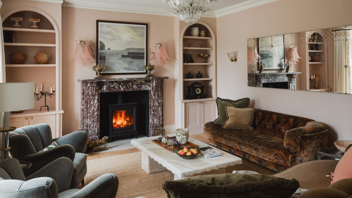 Painted in a calming plaster pink and adorned with opulent Murano wall lights is the open plan living room and kitchen