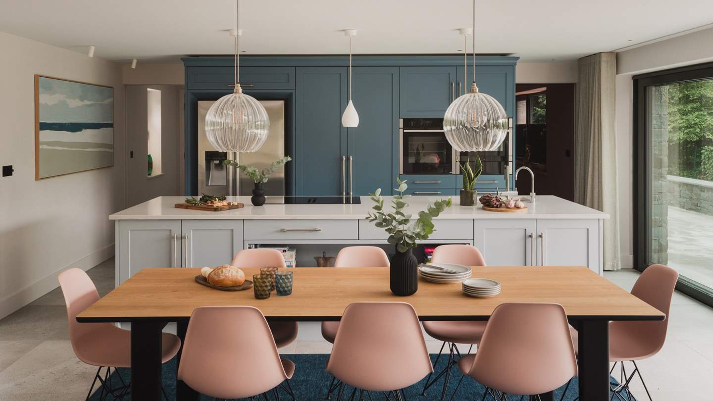 At the opposite end of the space awaits the sophisticated kitchen, featuring a bespoke, hand-crafted shaker kitchen, complete with a spacious white quartz island and a built-in pantry