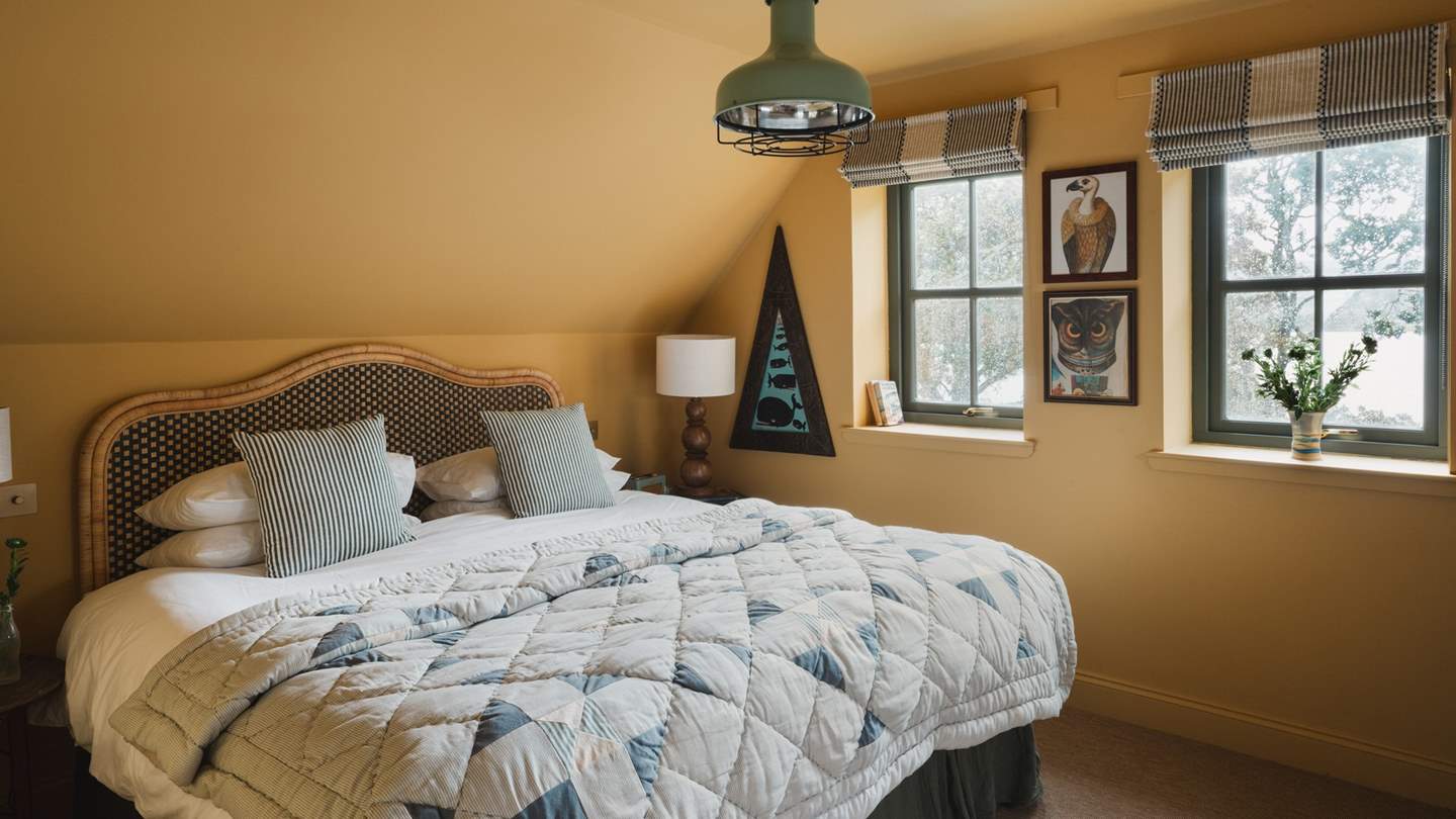 Drenched in warm mustard tones, the second bedroom invites for blissful repose