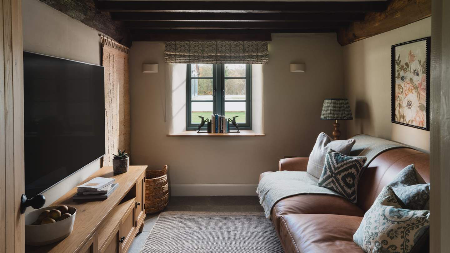 For cinematic evenings, retire to the snug, where a Smart TV rests before a tan leather sofa