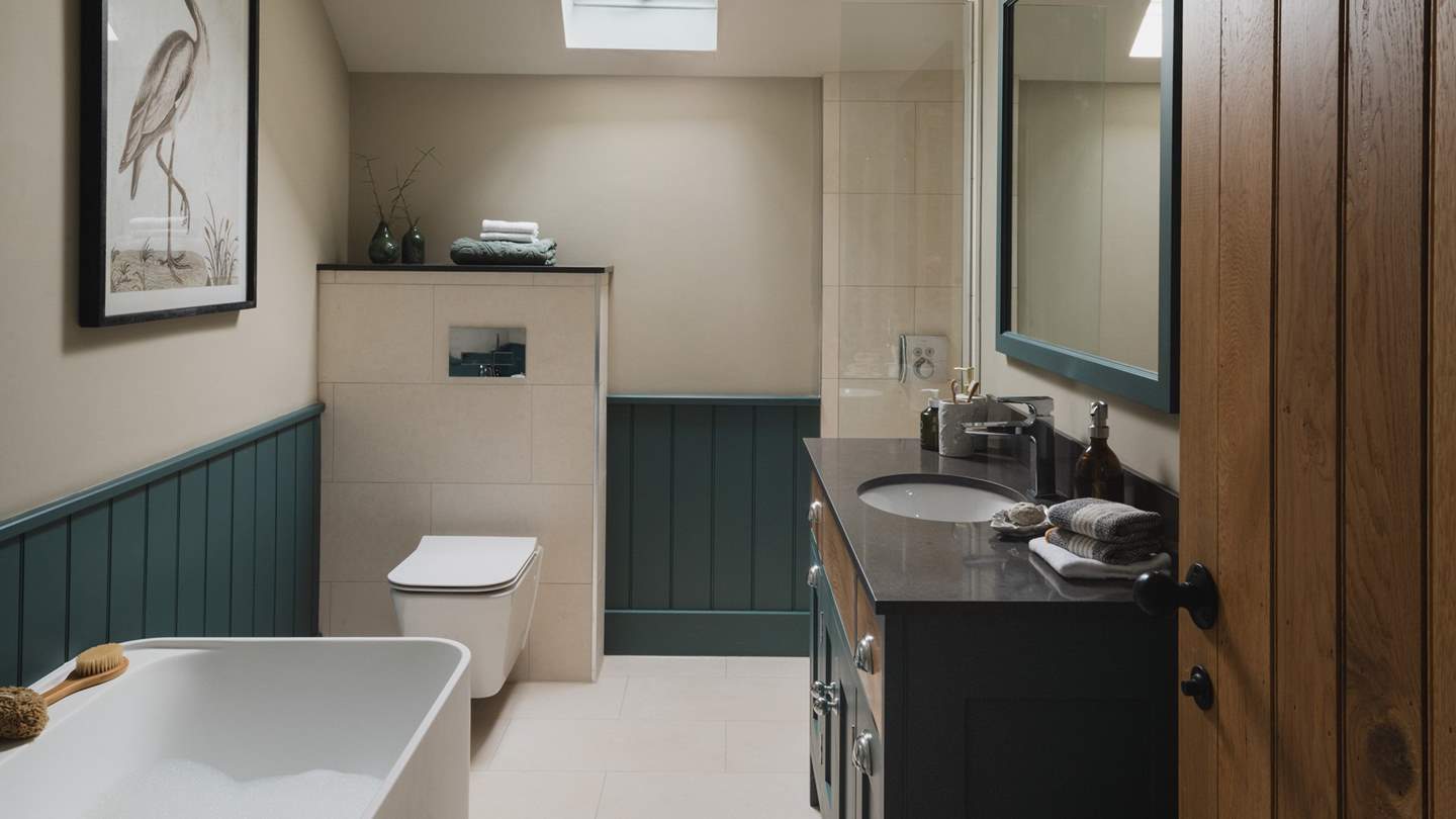 This space is complete with a freestanding bathtub and a separate rainfall shower