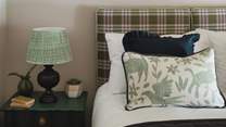 A bold tartan headboard sets the tone, paired with cushions and throws in harmonizing hues