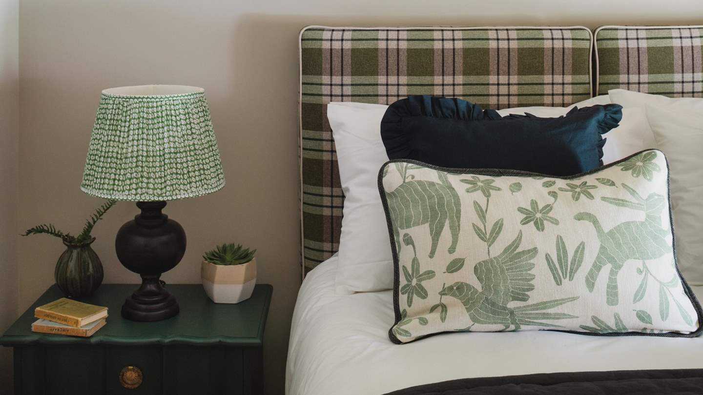A bold tartan headboard sets the tone, paired with cushions and throws in harmonizing hues