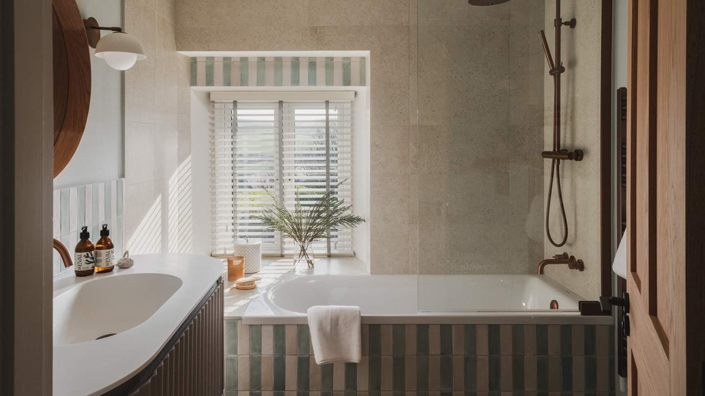 The first bathroom, located on the first floor, features a bath with a rainfall shower overhead