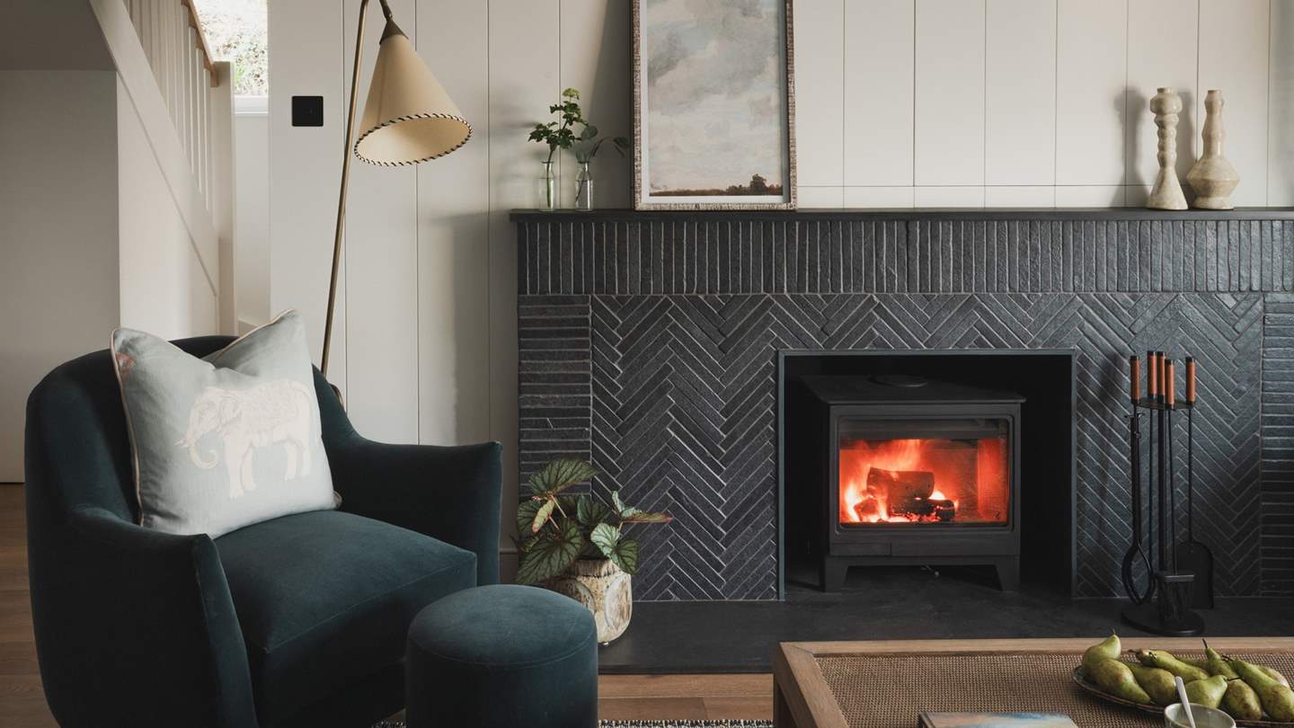 Exuding an irresistible ambience, a wood burning stove framed by a herringbone fireplace creates a striking focal point for a collection of Soho Home chairs and a handcrafted sofa