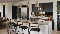 Four barstools rest before the kitchen island, seamlessly positioned to watch the culinary star of your party in action