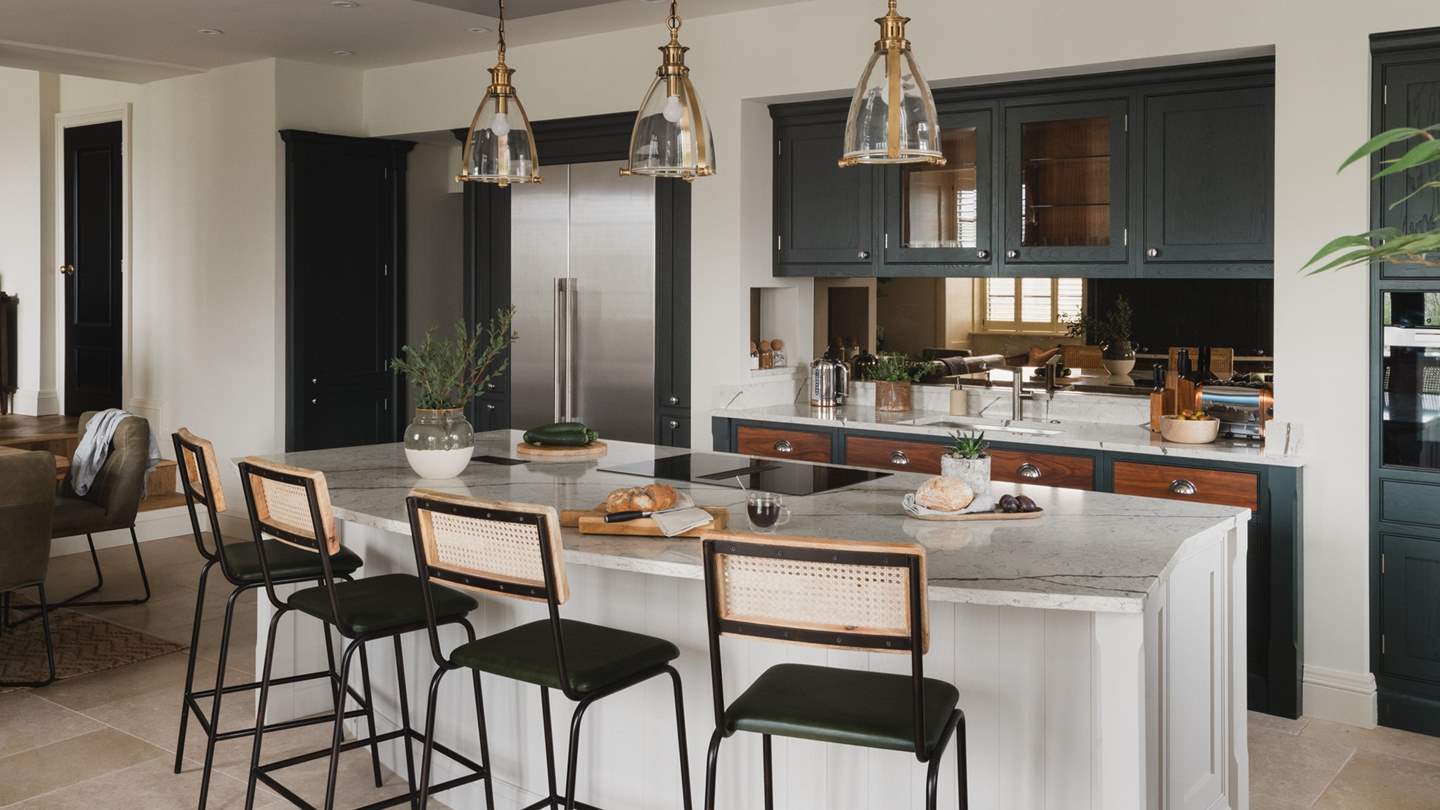 Four barstools rest before the kitchen island, seamlessly positioned to watch the culinary star of your party in action