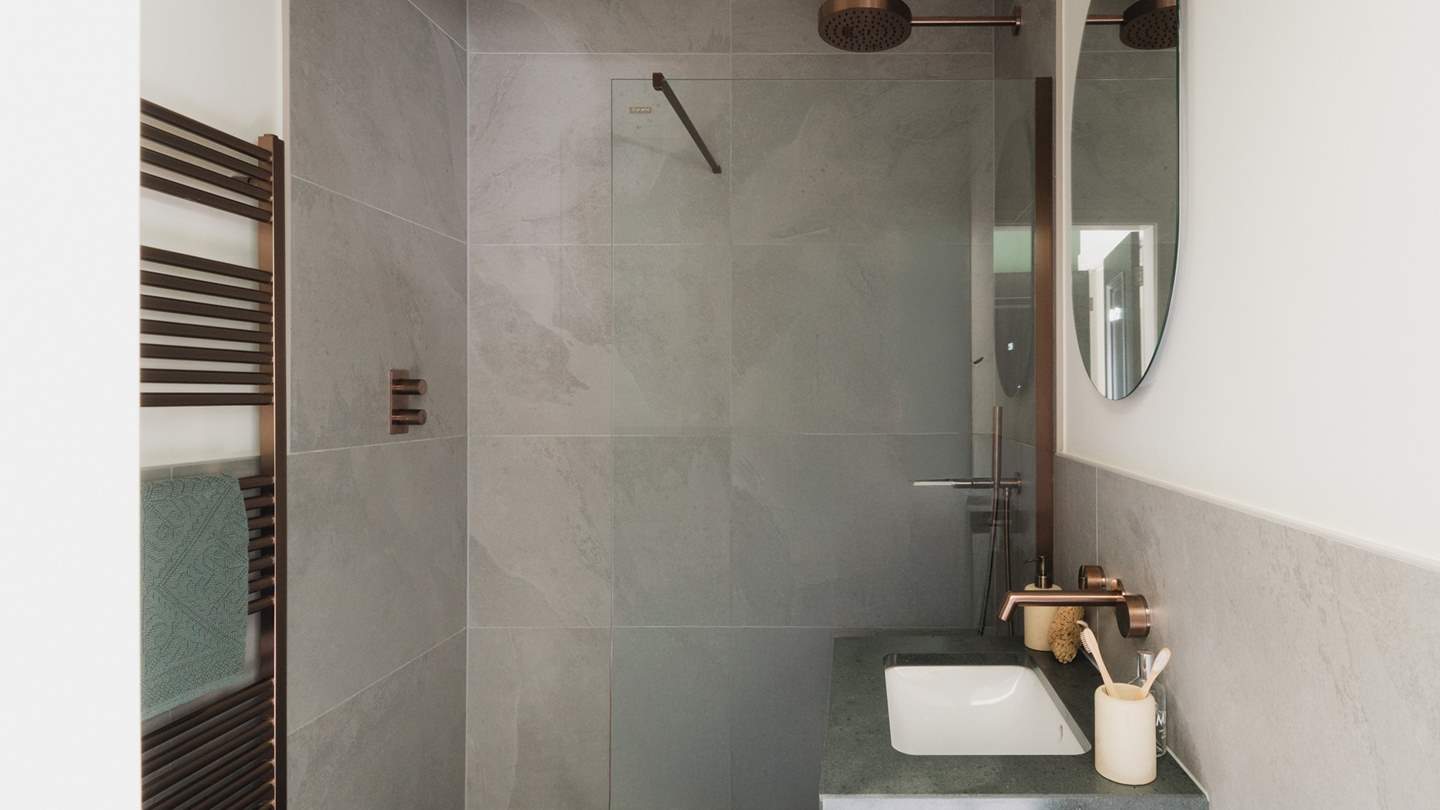 You’ll find a large walk-in shower with a rainfall head within the ensuite with rich copper fixtures