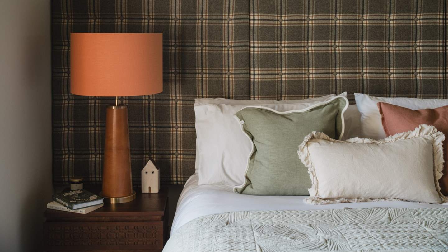 A tartan headboard and orange lamps resting atop the bedside tables, ensuring a calming glow for literary nightcaps