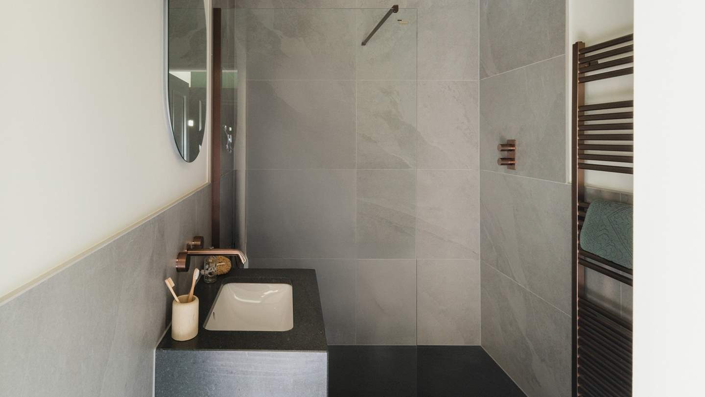 Crafted for ultimate serenity, the ensuite bathroom boasts a rainfall shower, complemented by opulent copper details throughout