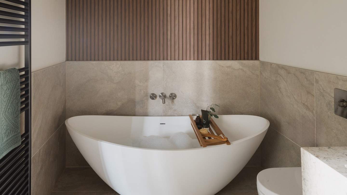 A modern freestanding slipper bathtub invites relaxing self-care rituals