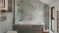Positioned on the first floor, the family bathroom is beautifully designed with tiles in a calming palette inspired by the coast